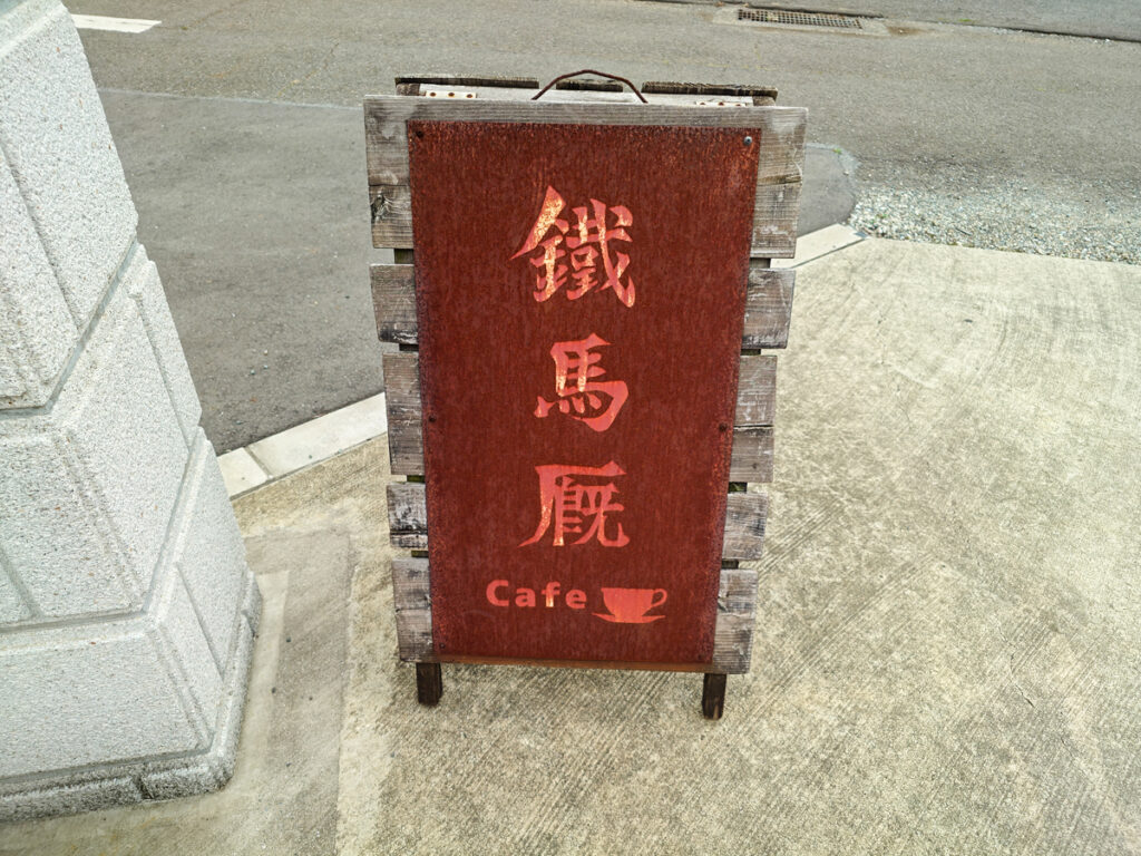 カフェ鐵馬厩の看板。赤い板に鐵馬厩Cafeと書かれている