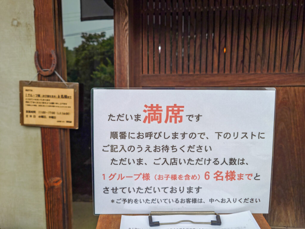 カフェ鐵馬厩の入口に出た満席案内板。1グループ6名まで、予約客は入店可と書かれている